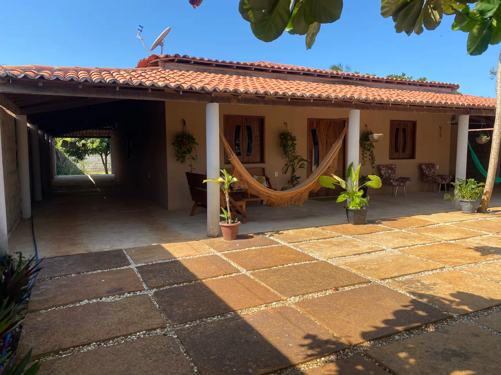 Frente da casa com varanda de telhado colonial e redes de descanso